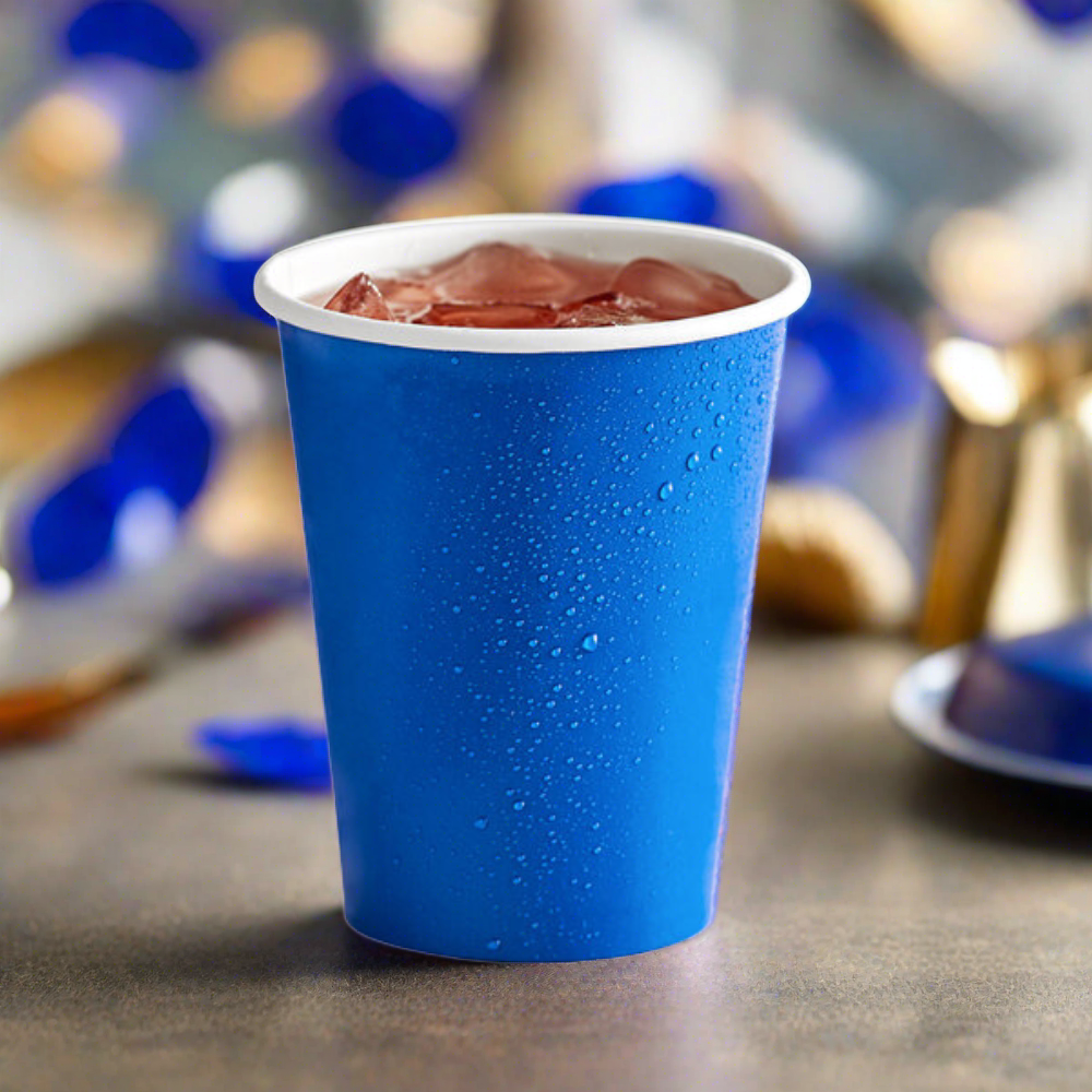 cobalt blue, 9 oz paper party cup for hot and cold drinks, sitting on table with blue confetti