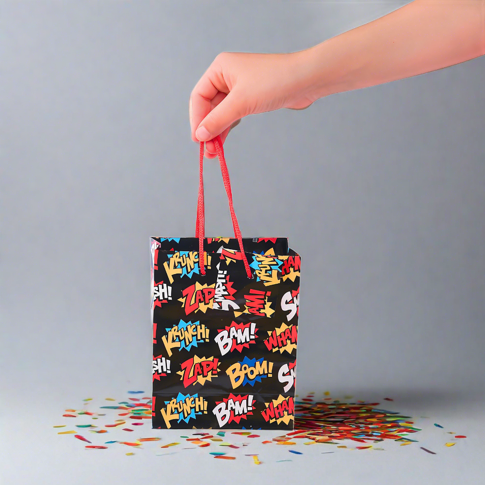person holding mini superhero party favor treat bags with slogans