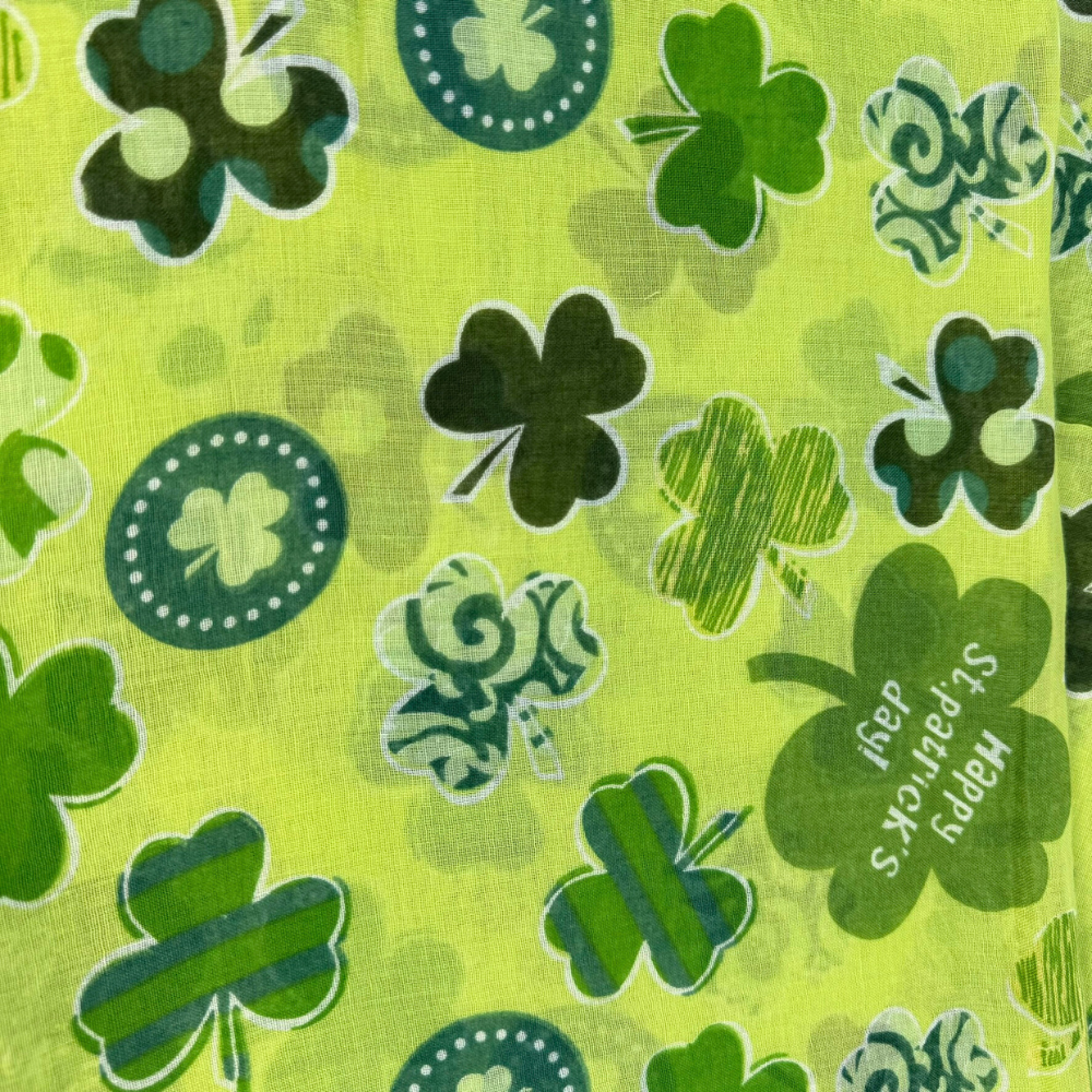 woman wearing a St. Patrick's Day green infinity scarf with different colors of green clovers in unique patterns close-up of pattern